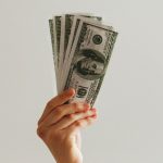 Hand holding stack of US dollar bills