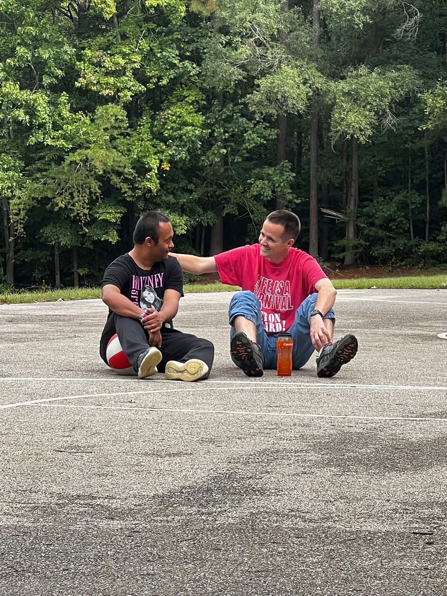 Two people sitting on outdoor court.