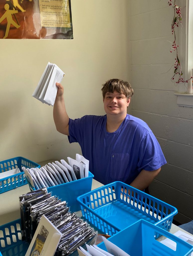 Person organizing mail into blue baskets.