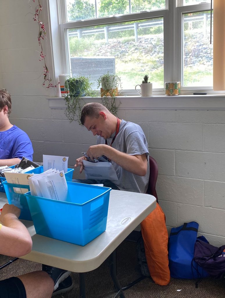 Person organizing papers at desk with blue bins.
